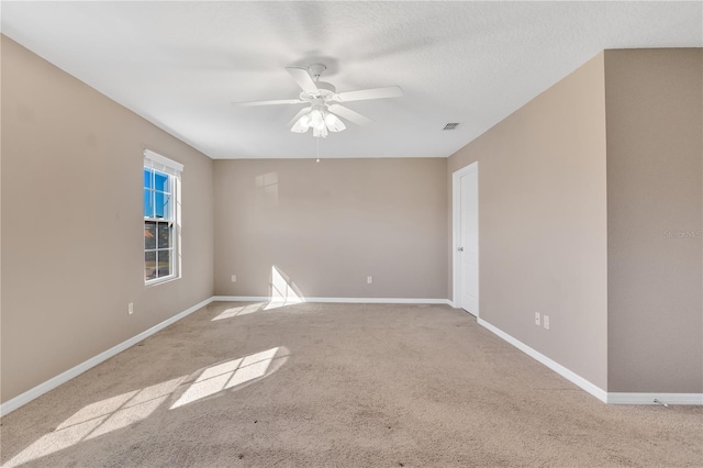 carpeted empty room with baseboards, visible vents, ceiling fan, and a textured ceiling