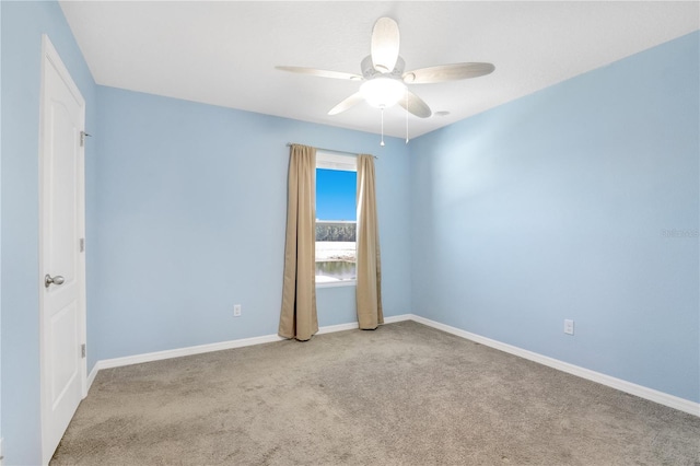 carpeted empty room with a ceiling fan and baseboards