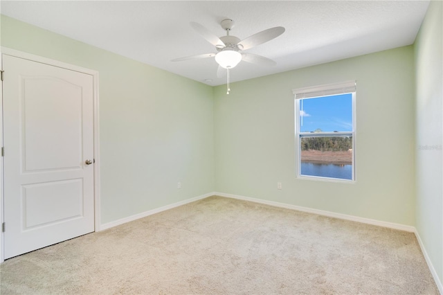 carpeted spare room featuring ceiling fan and baseboards