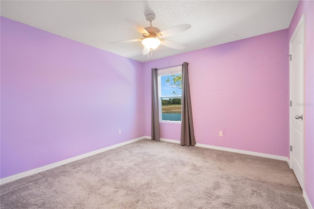 spare room featuring light carpet, ceiling fan, a textured ceiling, and baseboards