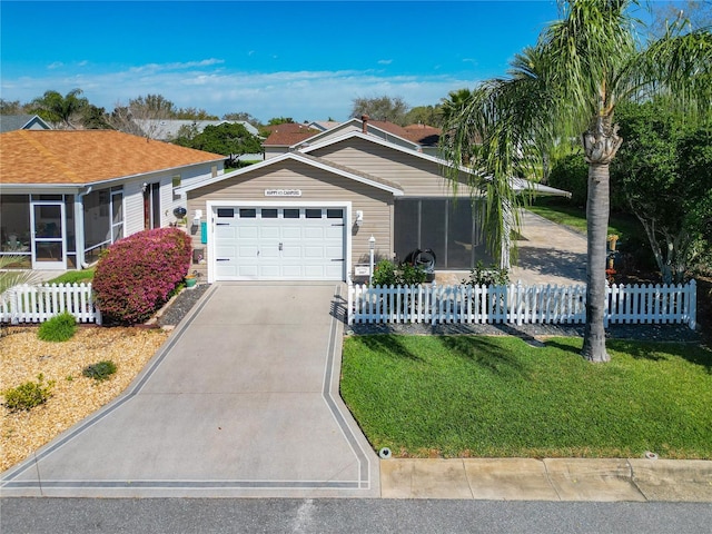 view of front of house with a fenced front yard, a front yard, a sunroom, a garage, and driveway