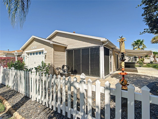 view of front facade featuring a sunroom, fence, and an attached garage