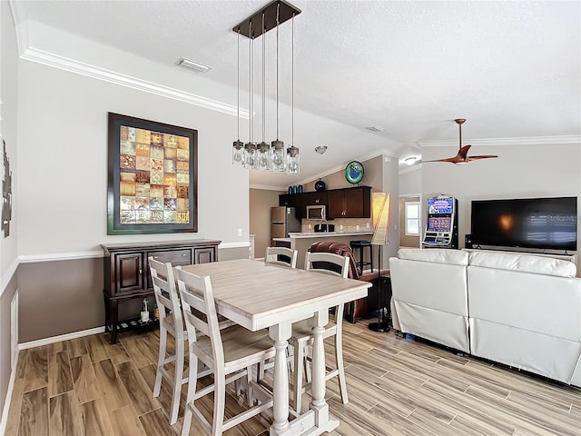 dining space featuring lofted ceiling, visible vents, crown molding, and wood finish floors