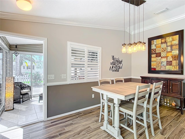 dining area with baseboards, visible vents, ornamental molding, and wood finish floors