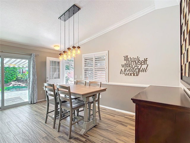 dining room featuring ornamental molding, lofted ceiling, a textured ceiling, and wood finished floors