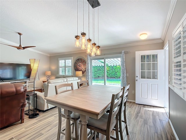 dining area featuring baseboards, light wood finished floors, a textured ceiling, and crown molding