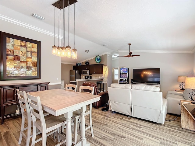 dining room with ceiling fan, visible vents, vaulted ceiling, ornamental molding, and wood tiled floor