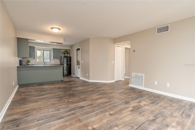 unfurnished living room featuring dark wood-style floors and visible vents