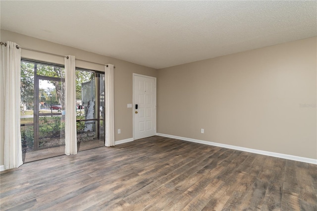 unfurnished room with dark wood-type flooring, a textured ceiling, and baseboards