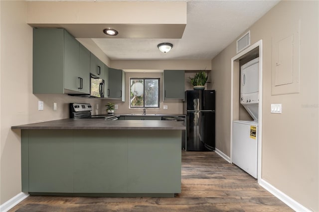 kitchen with stacked washer and dryer, dark countertops, electric range, freestanding refrigerator, and a peninsula