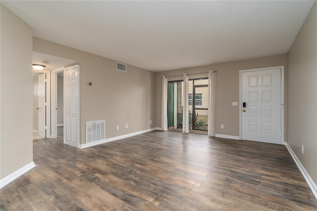 interior space with dark wood-style flooring, visible vents, and baseboards