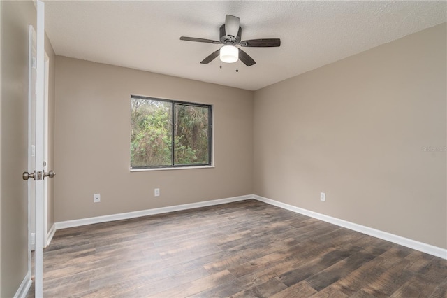 empty room with a textured ceiling, dark wood-type flooring, a ceiling fan, and baseboards