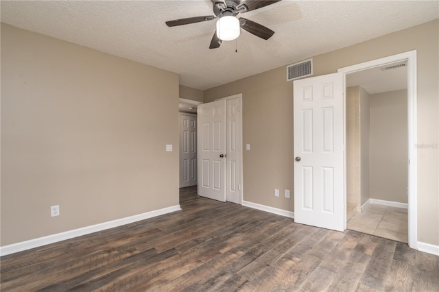 unfurnished bedroom with dark wood-style floors, visible vents, baseboards, and a textured ceiling