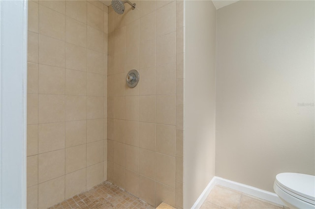 bathroom with tiled shower, tile patterned floors, toilet, and baseboards