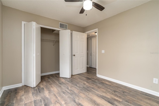 unfurnished bedroom with dark wood-style flooring, a closet, visible vents, a ceiling fan, and baseboards