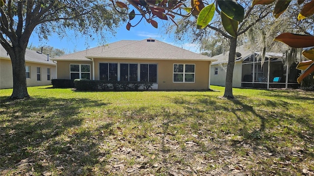 back of property with a lawn and stucco siding