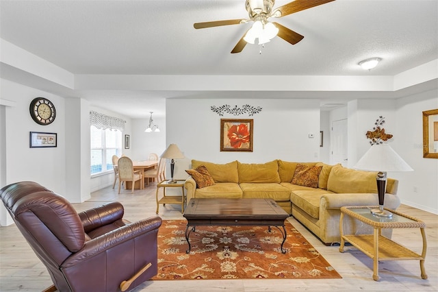 living area with a ceiling fan, baseboards, light wood-style flooring, and a textured ceiling