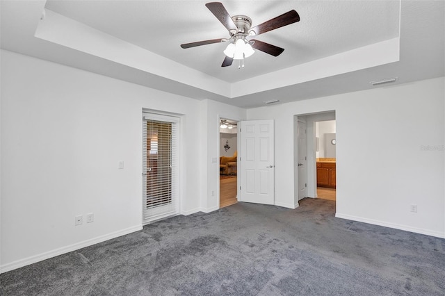 unfurnished bedroom featuring visible vents, baseboards, access to exterior, a tray ceiling, and dark colored carpet