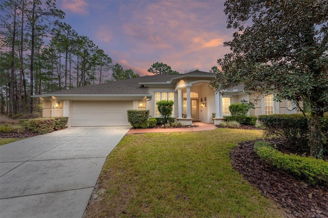 view of front of house with a garage, concrete driveway, a lawn, and stucco siding