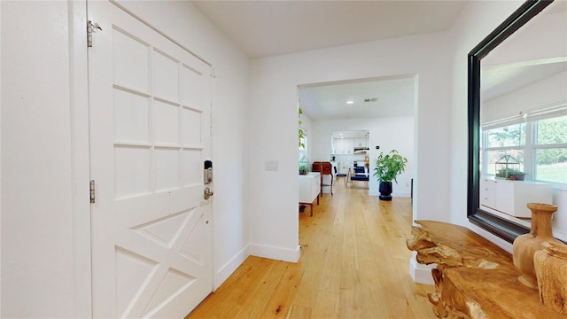 foyer with baseboards, visible vents, and light wood finished floors