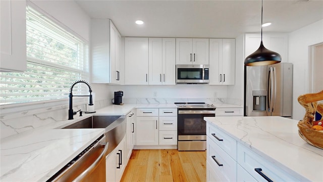 1930 Hilltop Dr, Mount Dora, FL 32757 - kitchen featuring light stone counters, stainless steel appliances, white cabinetry, a sink, and light wood-type flooring