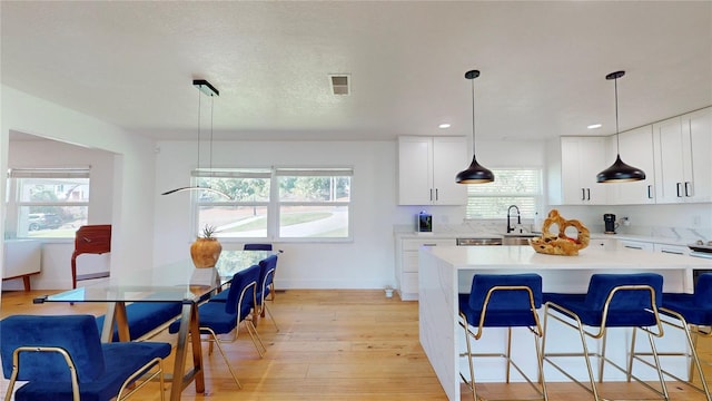 1930 Hilltop Dr, Mount Dora, FL 32757 - kitchen with light wood finished floors, a kitchen bar, white cabinetry, and light countertops