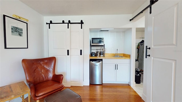 1930 Hilltop Dr, Mount Dora, FL 32757 - kitchen featuring light countertops, stainless steel microwave, light wood-style flooring, a barn door, and a sink