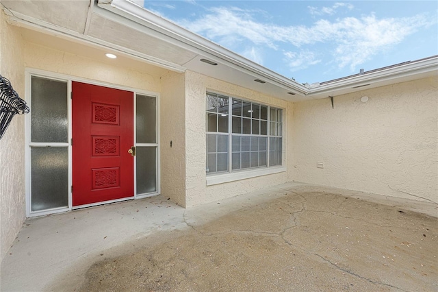 view of exterior entry featuring a patio and stucco siding