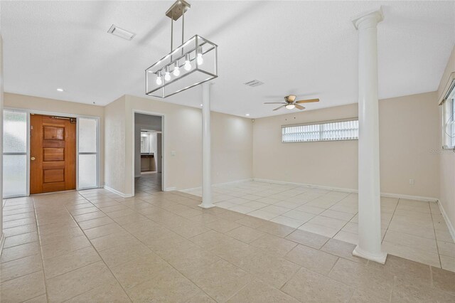 spare room with light tile patterned floors, decorative columns, and a ceiling fan