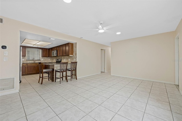 living area with ceiling fan, light tile patterned floors, visible vents, and baseboards