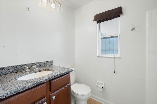 bathroom with toilet, baseboards, and vanity