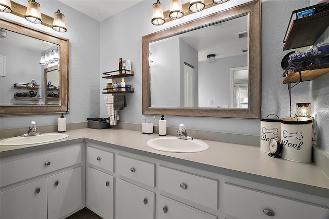 full bathroom featuring double vanity, a sink, and a textured wall