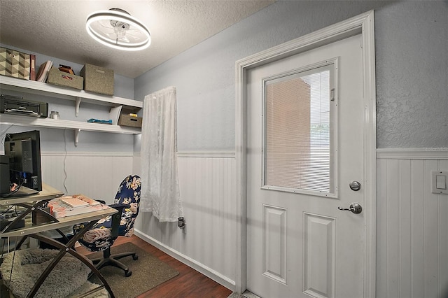 office space featuring a textured ceiling, wainscoting, and wood finished floors