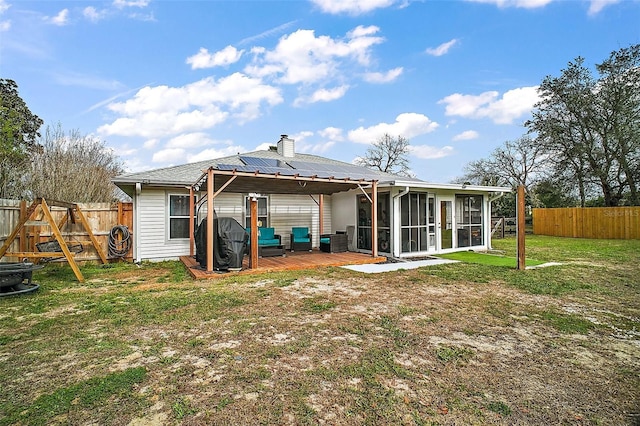 back of property with a sunroom, a fenced backyard, a yard, and a deck