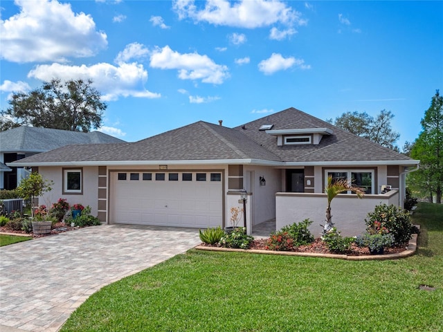 view of front of property with an attached garage, a shingled roof, decorative driveway, stucco siding, and a front yard