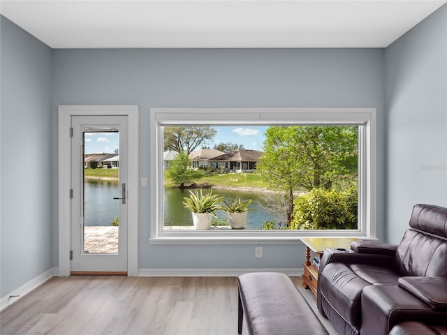 living area featuring a water view, wood finished floors, and baseboards