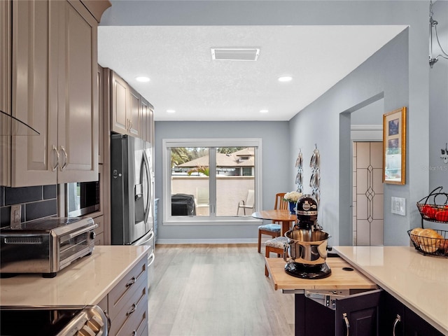 kitchen with a toaster, visible vents, light countertops, light wood-style flooring, and range