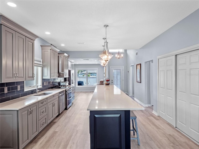 kitchen featuring tasteful backsplash, a kitchen island, gray cabinets, light countertops, and a sink