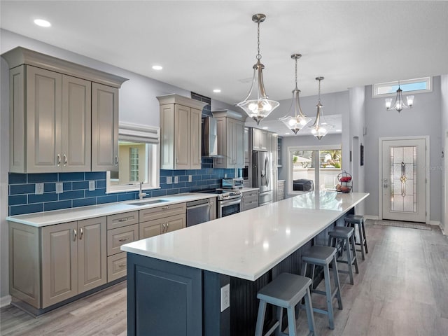 kitchen featuring a kitchen breakfast bar, stainless steel appliances, a sink, and gray cabinetry