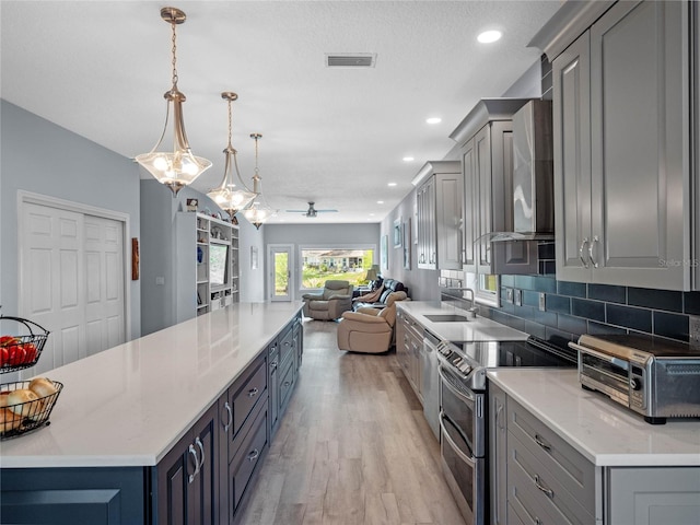 kitchen with appliances with stainless steel finishes, open floor plan, a sink, and gray cabinetry