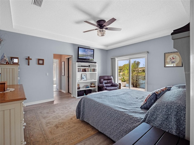 bedroom featuring a textured ceiling, wood finished floors, visible vents, and baseboards