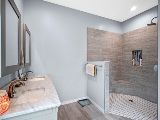 bathroom featuring wood finish floors, a sink, baseboards, and walk in shower