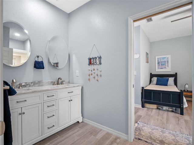 full bath featuring baseboards, visible vents, a sink, and wood finish floors