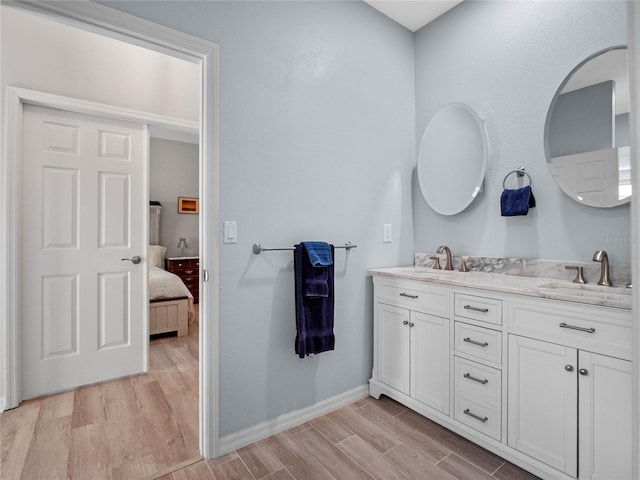 bathroom with double vanity, a sink, ensuite bath, and wood finished floors