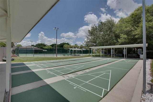 view of community with a tennis court, fence, and shuffleboard