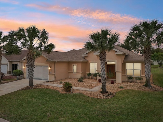 single story home featuring a garage, a yard, and stucco siding