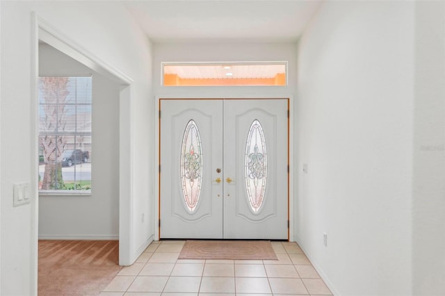 entrance foyer with french doors, light colored carpet, and light tile patterned floors