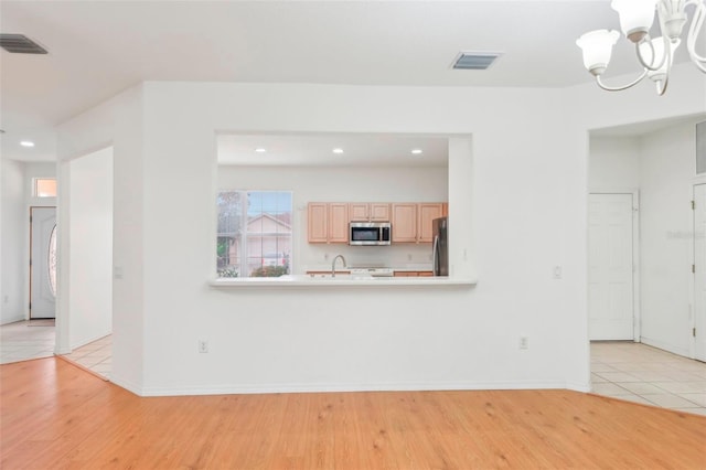 unfurnished living room featuring light wood-style floors, visible vents, and a chandelier