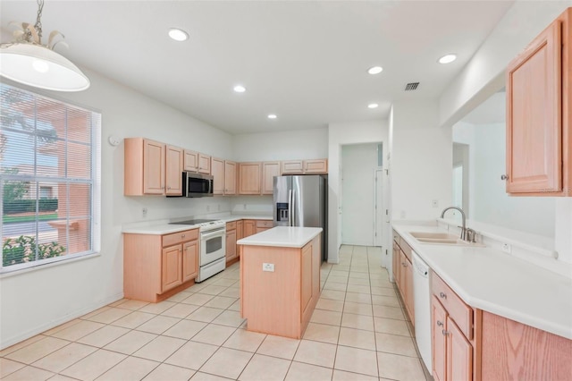 kitchen featuring visible vents, a kitchen island, appliances with stainless steel finishes, light brown cabinets, and a sink