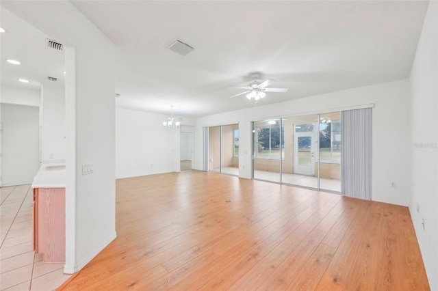 spare room with light wood-style flooring, visible vents, and ceiling fan with notable chandelier